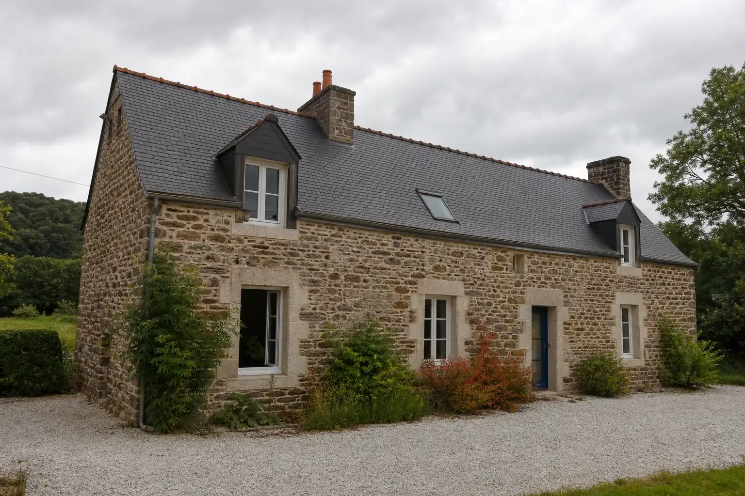 Façade extérieure d'une longère bretonne traditionnelle en pierre apparente, toiture d'ardoise, campagne d'Ille-et-Vilaine